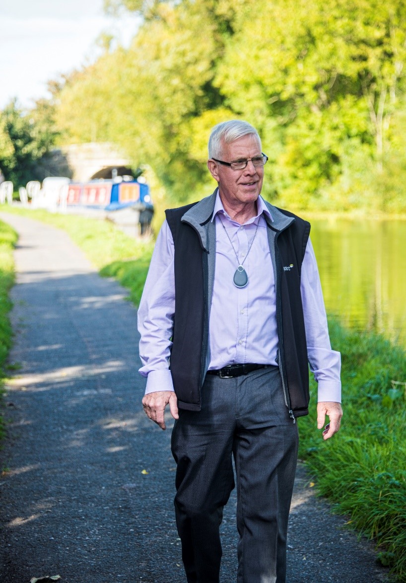 Man walking along canal path with alarm pendant